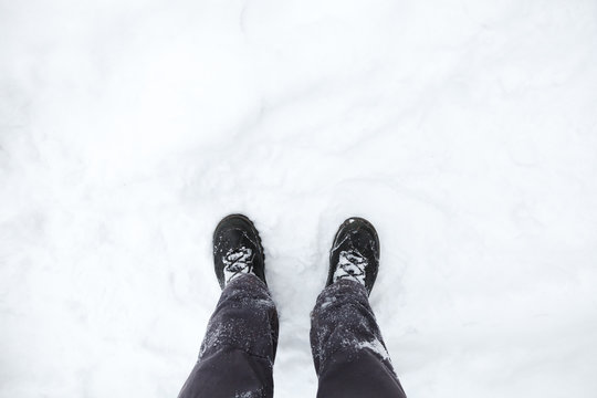 Male feet in black shoes on snow