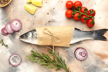 Tasty fresh seabass fish with vegetables and spices on color background