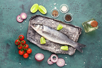 Plate with tasty fresh seabass fish on color background