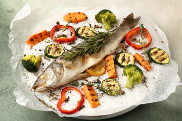 Fototapeta na wymiar Tasty cooked seabass fish and vegetables on parchment