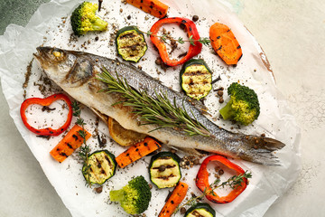 Tasty cooked seabass fish and vegetables on parchment