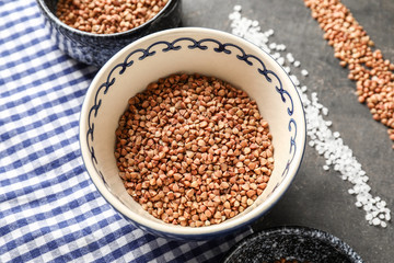 Bowl with raw buckwheat on grey table