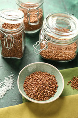Bowl and glass jars with raw buckwheat on table