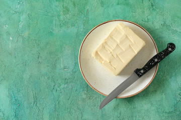 Plate with butter and knife on table
