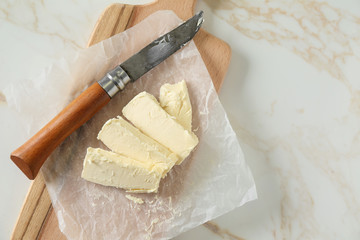 Pieces of butter and knife on wooden board