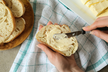 Woman spreading tasty bread with butter in kitchen