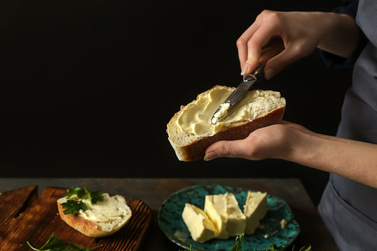 Woman spreading tasty bread with butter at table