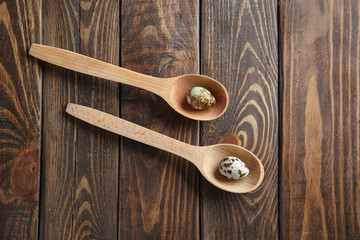 Fototapeta premium Spoons with quail eggs on wooden table