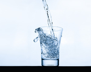 glass pouring clean water on a light background