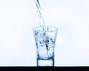 glass pouring clean water on a light background
