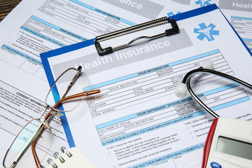 Health insurance forms with eyeglasses and stethoscope on table