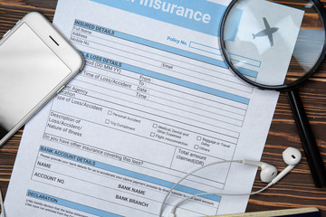 Travel insurance form with magnifier and mobile phone on table