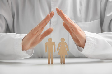 Female doctor with human figures on table, closeup. Health care insurance concept