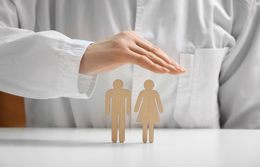 Female doctor with human figures on white table, closeup. Health care insurance concept