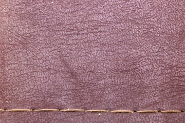 texture of red old leather with a seam of thread