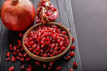 Ripe pomegranate and bowl with seeds on table