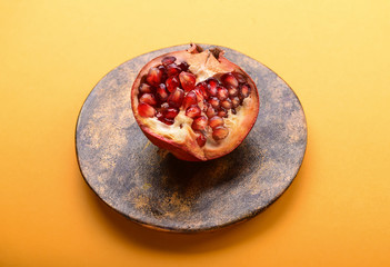 Plate with ripe pomegranate on color background