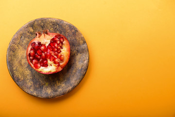 Plate with ripe pomegranate on color background