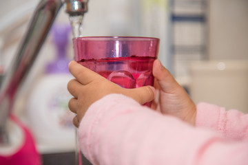 コップに水をくむ子供の手