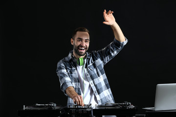 Male DJ playing music on dark background