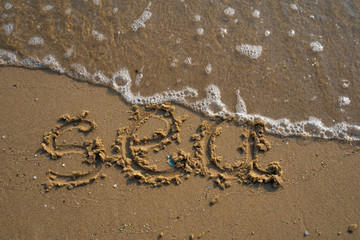 Vacation on the sand beach concept. Sea words written into the sand on the beach at Rayong, Thailand.