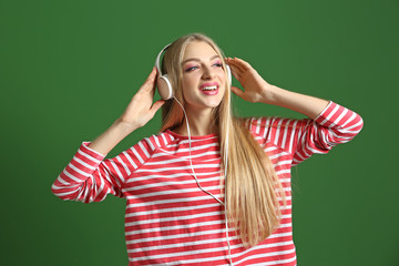 Beautiful young woman listening to music on color background