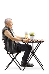 Old punk man sitting at a table and drinking beer