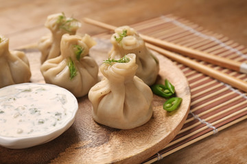 Plate with tasty dumplings and sauce on table