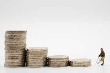 Miniature of broken legs man and coins stacking on white background. Insurance cost of sick and...