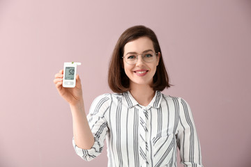 Diabetic woman with digital glucometer on color background