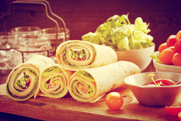 Tortilla wraps with ham cheese and vegetables, close up vintage view