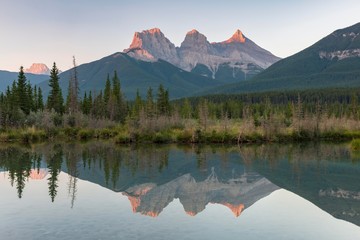 Three Sisters reflecting in calm water, morning atmosphere, Bow River, Canmore, Banff National Park, Alberta, Canada, North America