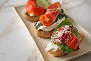 Plate with fresh tasty bruschettas on light background