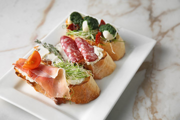 Plate with fresh tasty bruschettas on light background