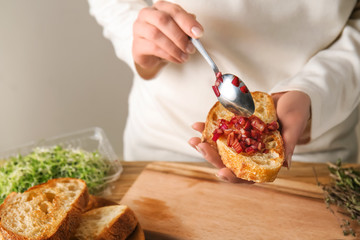 Woman preparing tasty bruschettas in kitchen