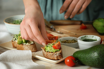 Woman preparing tasty bruschettas in kitchen, closeup