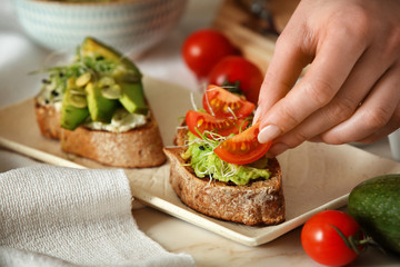 Woman preparing tasty bruschettas in kitchen, closeup