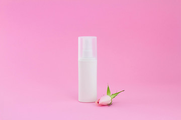 Blank packaging cosmetic pump bottle with rosebud on pink background, close up mockup cream spray object