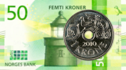 1 norwegian krone coin against 50 new norwegian krone banknote