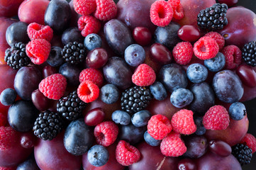 Background of fresh fruits and berries. Ripe blackberries, blueberries, plums, red berries, raspberries. Mix berries and fruits. Top view. Background berries and fruits. Black-blue and red food.