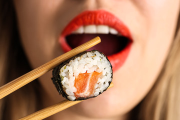 Woman eating tasty sushi roll, closeup