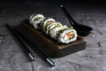 Plate with tasty sushi rolls on grey table