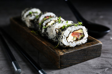 Plate with tasty sushi rolls on grey table