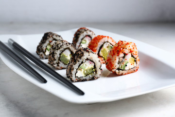 Plate with tasty sushi rolls on light table
