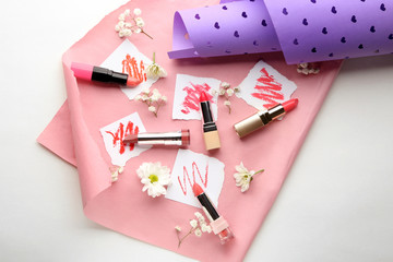 Composition with lipsticks and paper sheets on color background