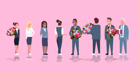businessmen congratulating businesswomen with happy 8 march womens day concept mix race men giving flowers women pink background full length horizontal