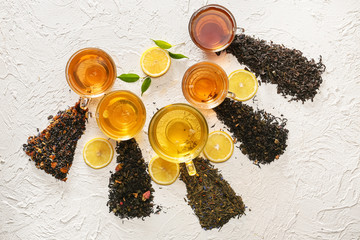 Cups with different types of tea and dry leaves on white background