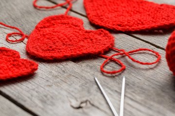 Three red knitted hearts on a gray wooden background, symbolizing love and family. Family relationship, bonds.