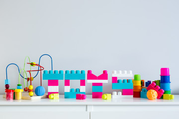 different toys and letters folded of colorful toy constructor with copy space over white wall