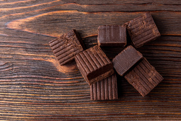 Chocolate toffees on dark wooden background.